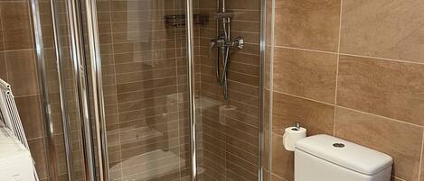 A bathroom with a glass-enclosed shower, a white toilet, and a washing machine.