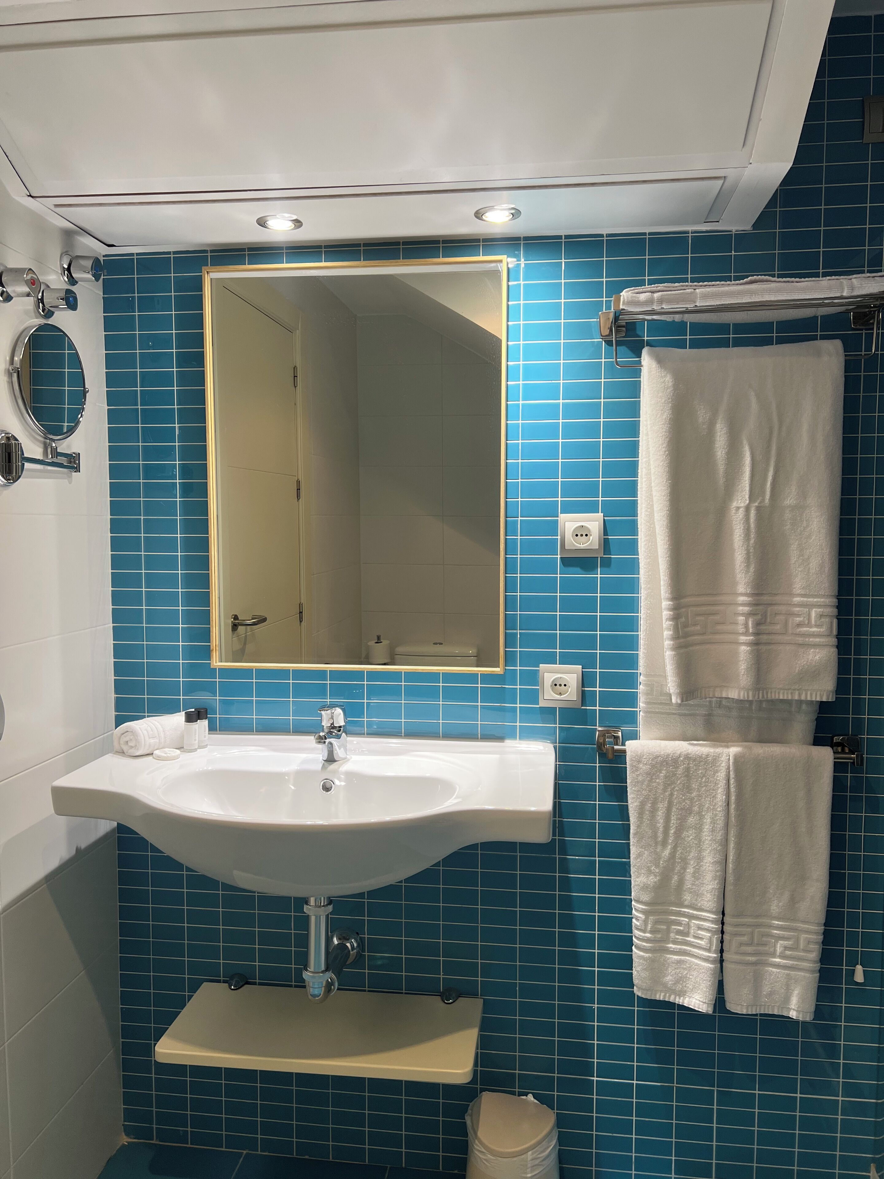 A bathroom with a sink, mirror, and blue tiled walls.