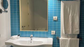 Une salle de bain avec un lavabo, un miroir et des murs recouverts de carreaux bleus.