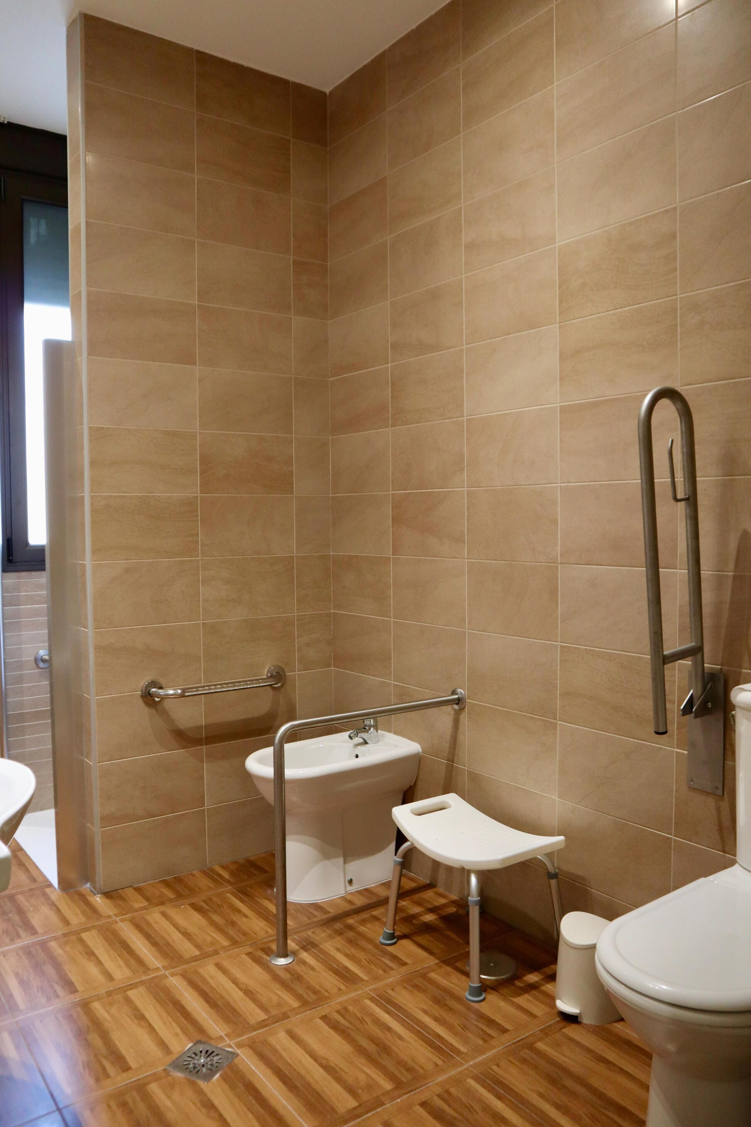 A bathroom with a wooden floor, a sink, a toilet, and a shower area.