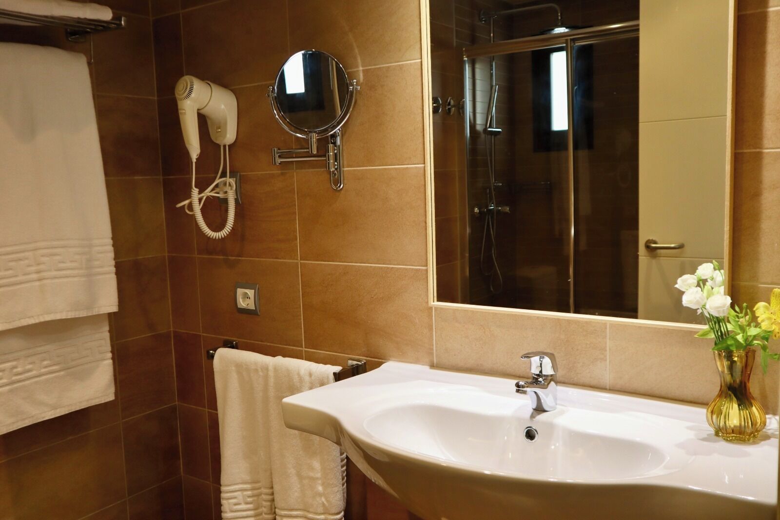 Un baño con lavamanos, espejo, secador de pelo y toallero.