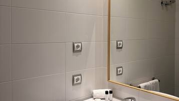 A modern bathroom with a white sink, a large mirror, and a towel rack.