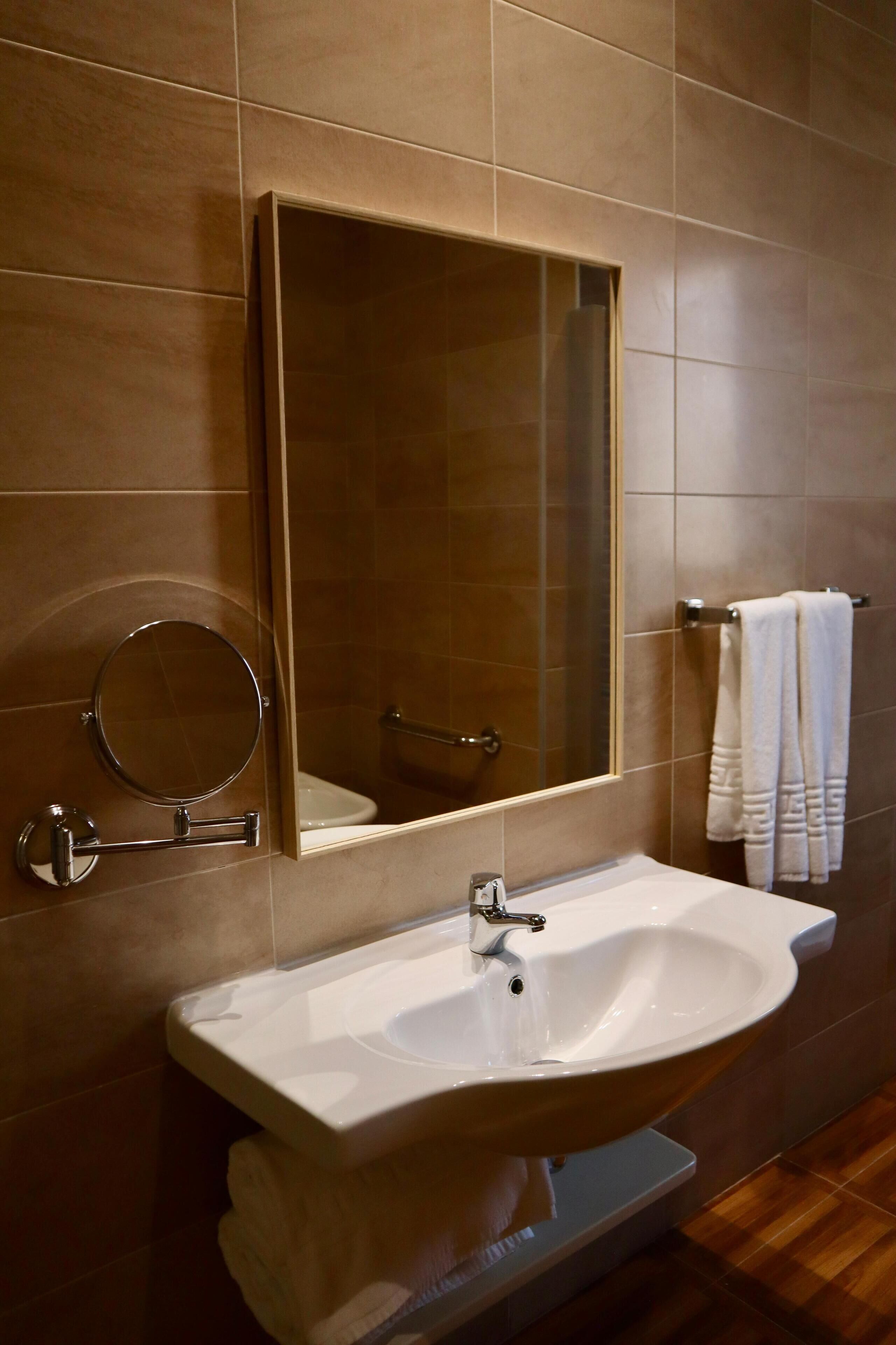 Un baño con un espejo grande, un lavabo y un perchero para toallas.