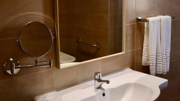 Un baño con un espejo grande, un lavabo y un perchero para toallas.