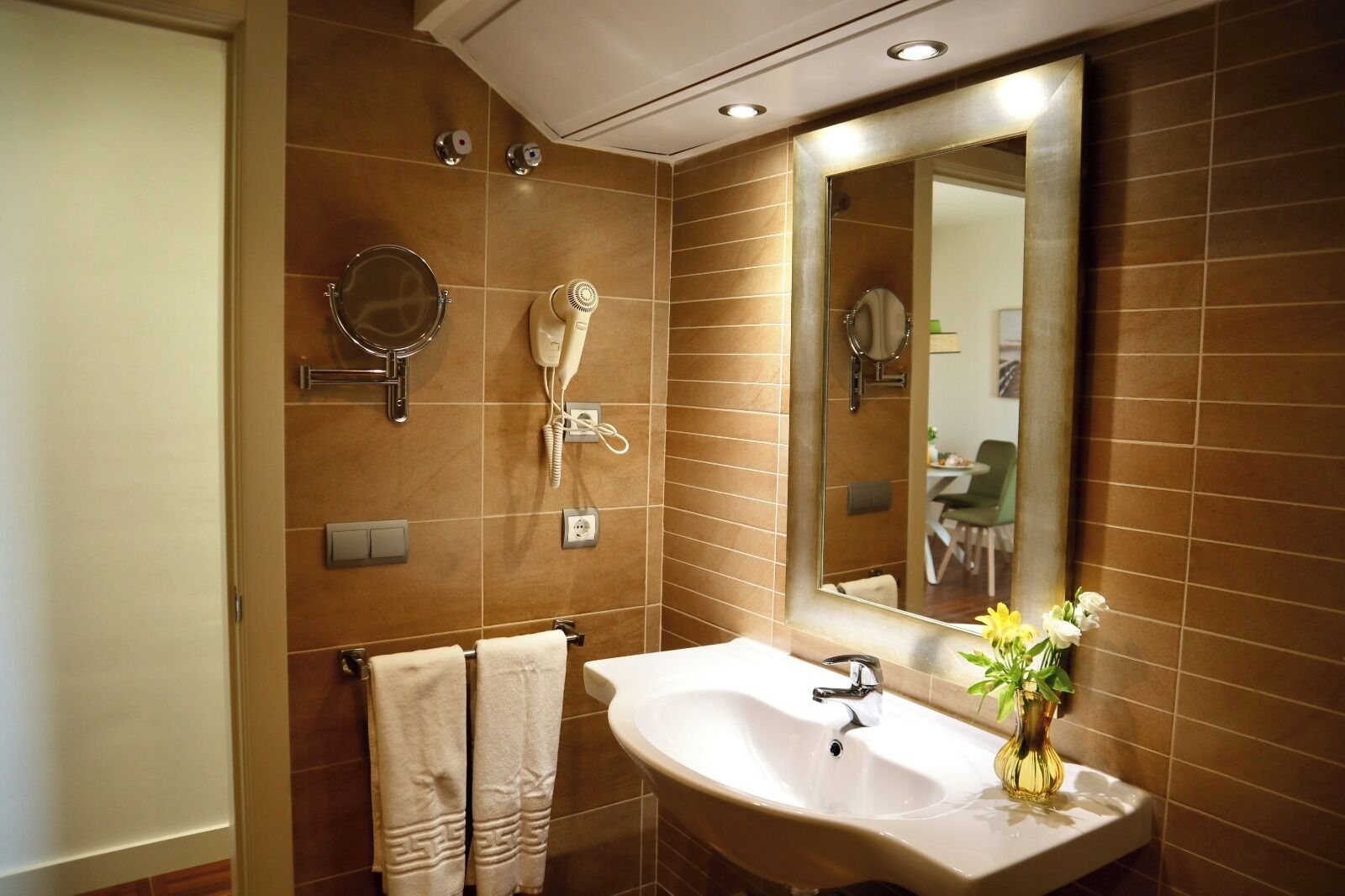 A bathroom with a sink, mirror, towel rack, and a wall-mounted hairdryer.
