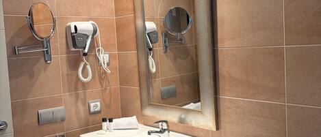 A modern bathroom with a large mirror, a sink, and a hairdryer on the wall.