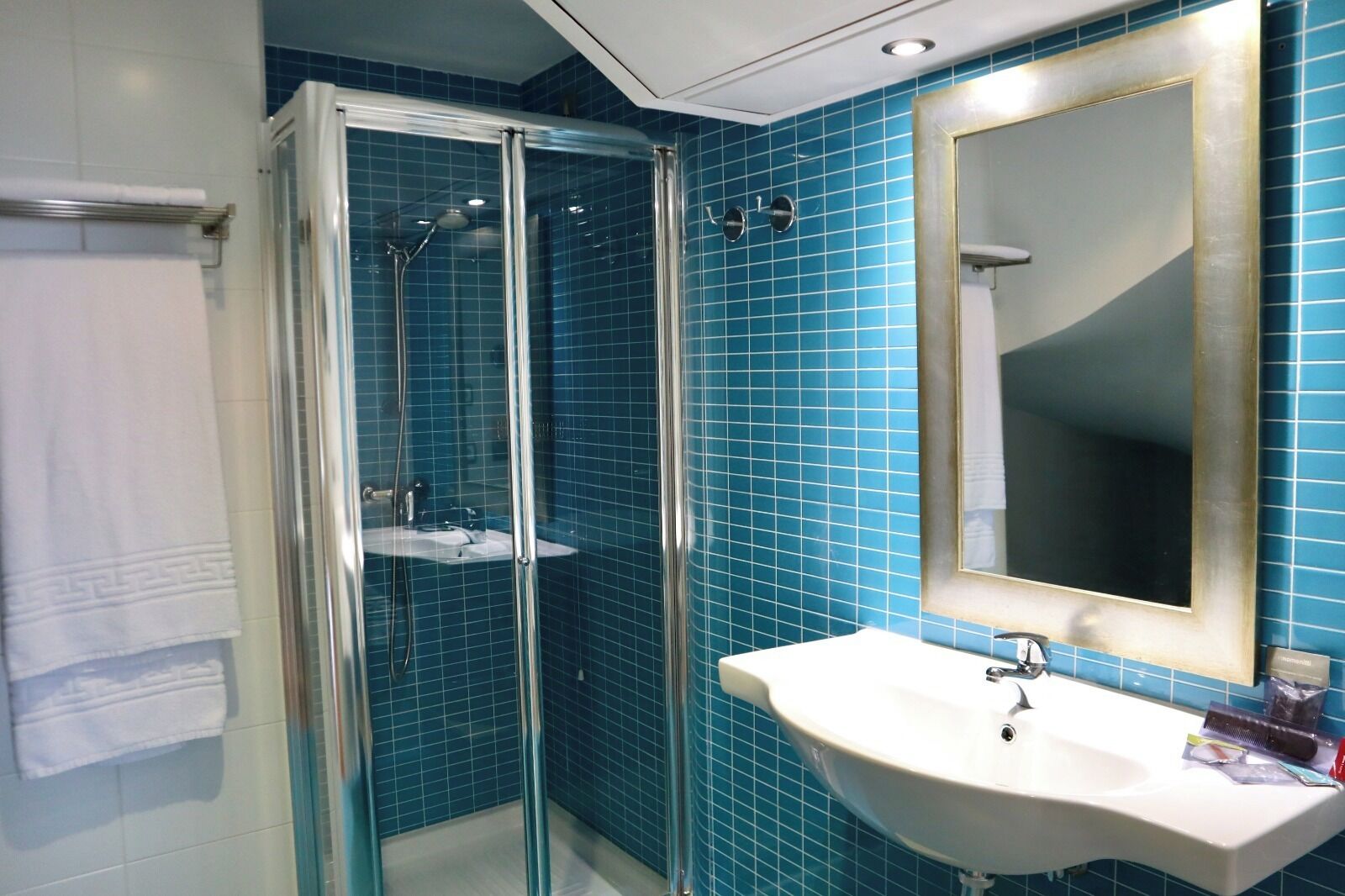 A bathroom with a glass-enclosed shower, a white sink, and a large mirror.