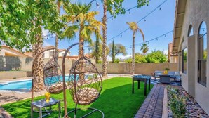A backyard with a swimming pool, hanging chairs, a table, and a patio area. - Pool, Fun & Relaxation | Stylish Scottsdale Stay (Scottsdale)