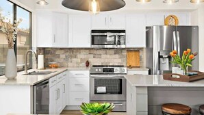 A modern kitchen with white cabinets, stainless steel appliances, and pendant lighting. - Pool, Fun & Relaxation | Stylish Scottsdale Stay (Scottsdale)