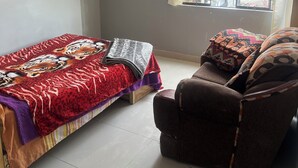 Una habitación con una cama, un sofá y una ventana que da a vistas de edificios.