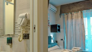 A hotel room with a bed, a TV, a hairdryer, and a shower area. - Luxury Herculaneum in Naples station train (Napoli)