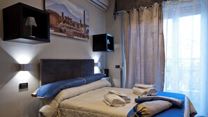 A hotel room with a bed, a TV mounted on the wall, and a window with curtains. - Luxury Herculaneum in Naples station train (Napoli)