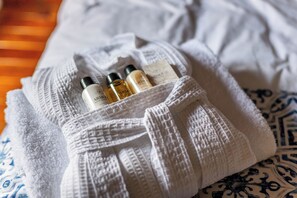 A white towel with toiletries on a bed with patterned bedding. - Villa Colonial, Centro de Coyoacán (Mexico City)