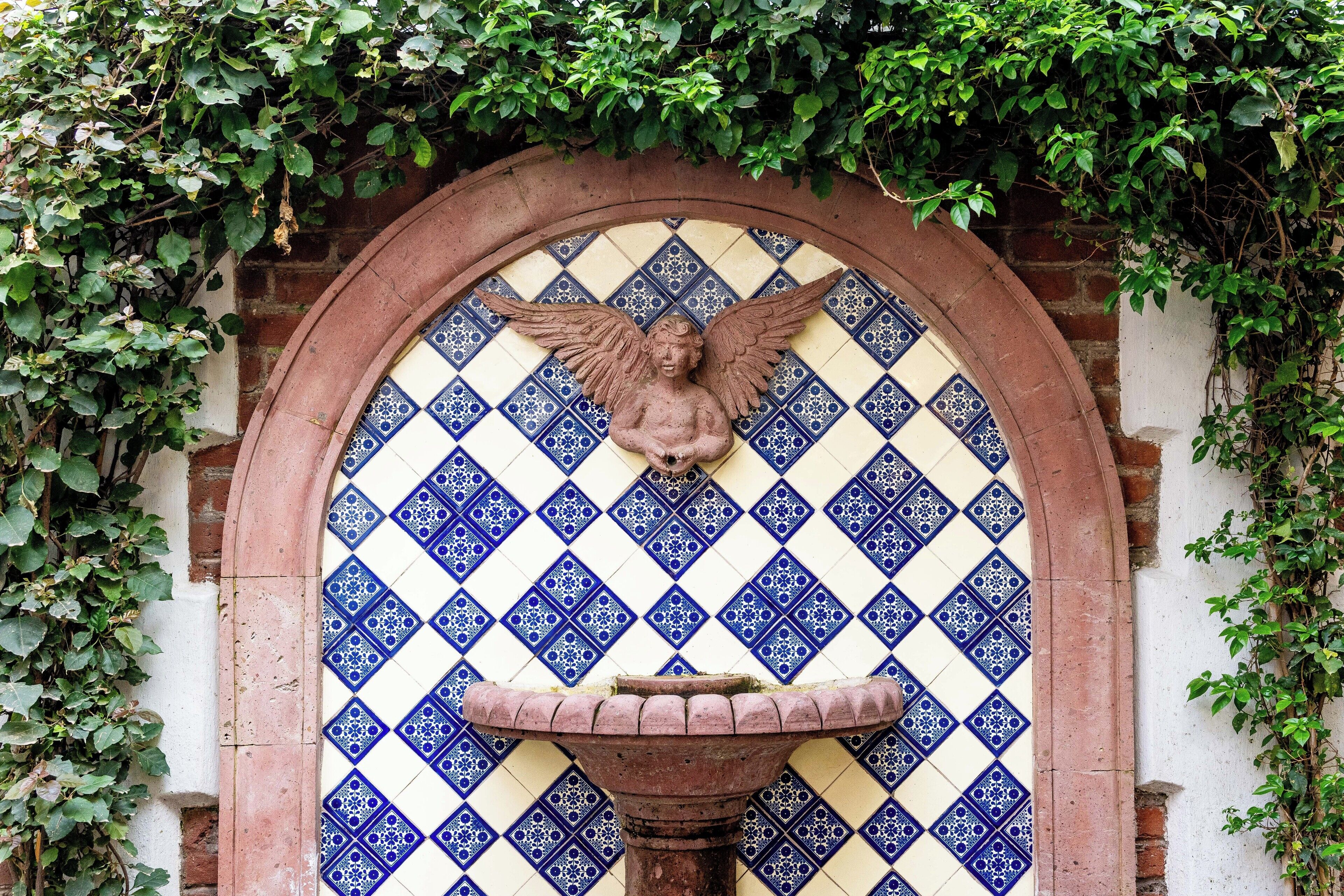 Pared de azulejos con un ángel decorativo y una fuente.