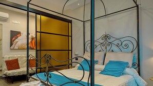 A four-poster bed with a metal frame, a sofa with a patterned cover, and a wall-mounted air conditioner. - Luxury Paestum in Naples station train (Napoli)