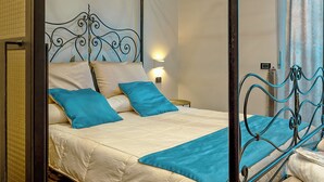 A four-poster bed with a metal frame, white bedding, and blue pillows. - Luxury Paestum in Naples station train (Napoli)