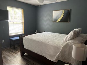 A bedroom with a bed, a bench, a window, and a painting on the wall. - 3-bedroom house in charming Jackson Springs. Not to far from the course. (Jackson Springs)