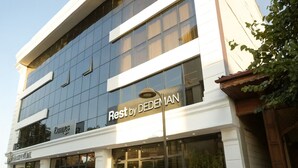 A hotel with a modern glass facade, a sign reading "Rest by DEDEMAN", and a visible entrance with a seating area outside. - Rest by Dedeman Sapanca (Sapanca)