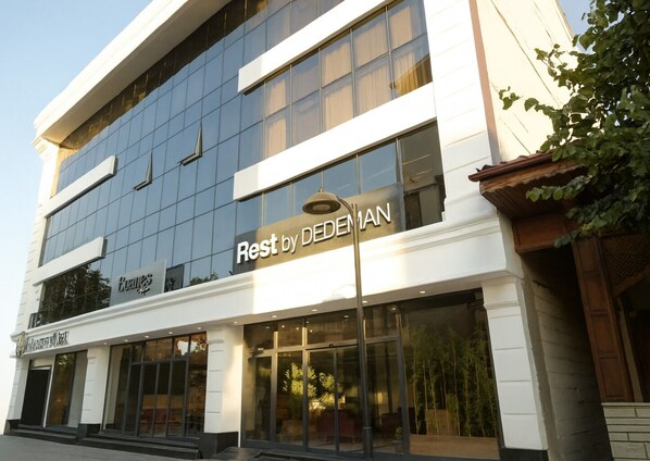 A hotel with a modern glass facade, a sign reading "Rest by DEDEMAN", and a visible entrance with a seating area outside. - Rest by Dedeman Sapanca (Sapanca)