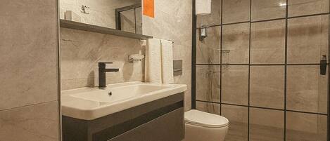 Un baño moderno con un espejo grande, un lavamanos y un inodoro.