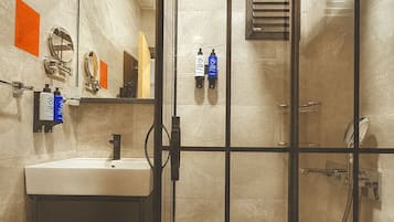 Un baño moderno con mampara de vidrio, lavamanos, espejo y zona de ducha.