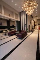 A spacious lobby with a modern chandelier, leather sofas, and a clean, minimalist design.