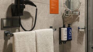 Casa de banho moderna com secador de cabelo, porta-toalhas, espelho e dispensador de produtos de higiene.