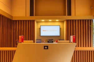 A conference room with a screen displaying 'Rest by DEDEMAN' and a podium with a microphone.