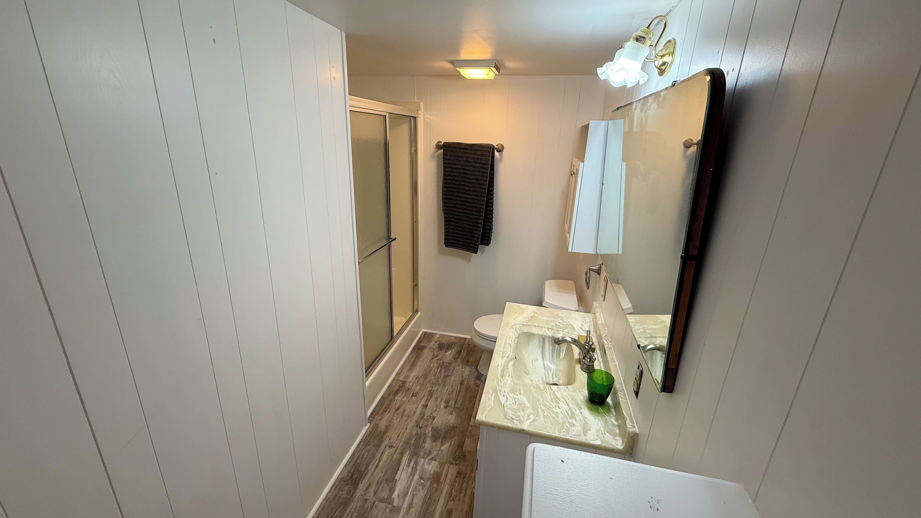 A bathroom with a shower, toilet, sink, and mirror.