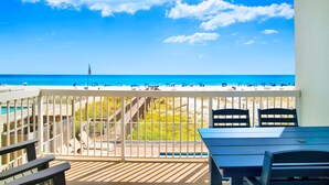 A balcony with a view of the beach, a flag, and a table with chairs. - Great Rates-Pet Friendly-Beachfront-Amazing View (Gulf Shores)