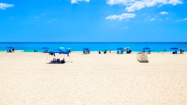 A beach with clear skies, blue umbrellas, and a few people. - Great Rates-Pet Friendly-Beachfront-Amazing View (Gulf Shores)