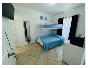 A room with a bunk bed, a small desk, a potted plant, and a mirror.