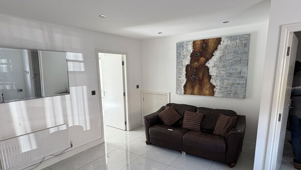 A modern living room with a large mirror, a brown leather sofa, and a textured wall art piece. - Joel’s place is in the heart of Manchester close to    Everywhere 8mins drive to (Manchester)
