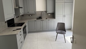 A modern kitchen with grey cabinets, a built-in oven, and a grey chair. - Joel’s place is in the heart of Manchester close to    Everywhere 8mins drive to (Manchester)