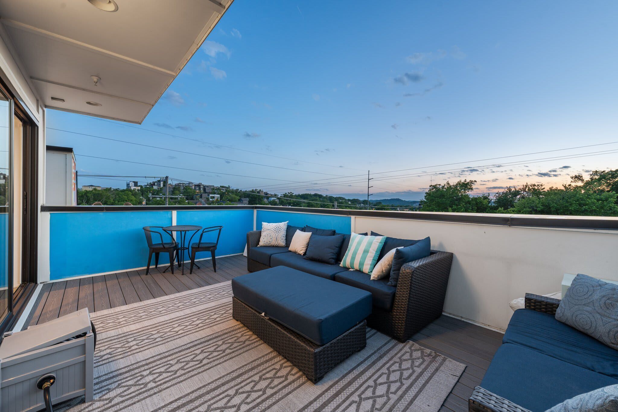 A rooftop terrace with a blue wall, a sofa set, a table, and chairs.
