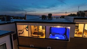 Een modern gebouw met een jacuzzi op het dak, een balkon met uitzicht en een goed verlicht interieur.