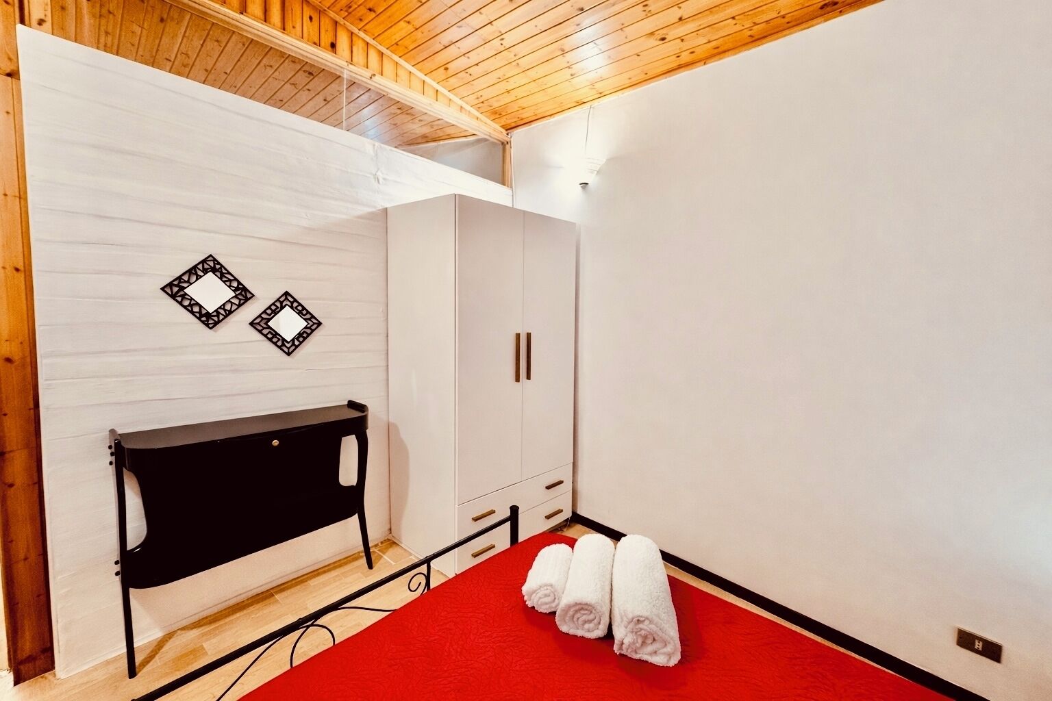 A room with a bed, a wardrobe, and a red carpet.
