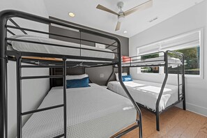 Una habitación con literas, ventilador de techo y ventana con vistas.