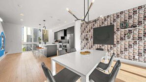 A modern kitchen with a white dining table, black chairs, and a patterned wall.