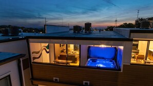 A modern building with a rooftop jacuzzi, a dining area, and a bedroom with a window view.