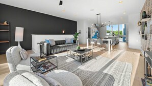 A modern living room with a sofa, coffee table, and a dining area with chairs.