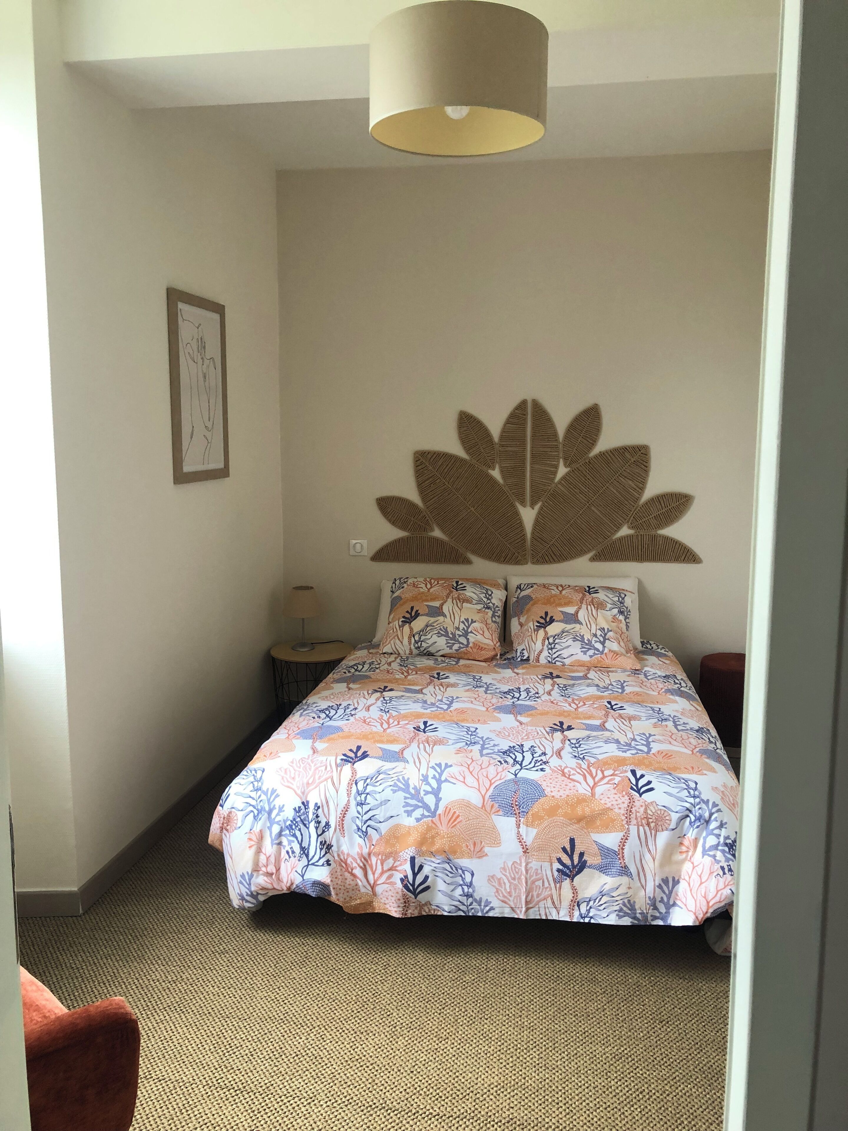 A bedroom with a bed, a wall art piece, and a lamp.