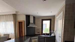 A modern kitchen with dark cabinetry, a stainless steel range hood, and a tiled backsplash.