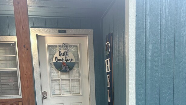 Una porta d'ingresso con un cartello che dice 'Welcome', un tappeto rosso e dei gradini in legno che portano a un portico.