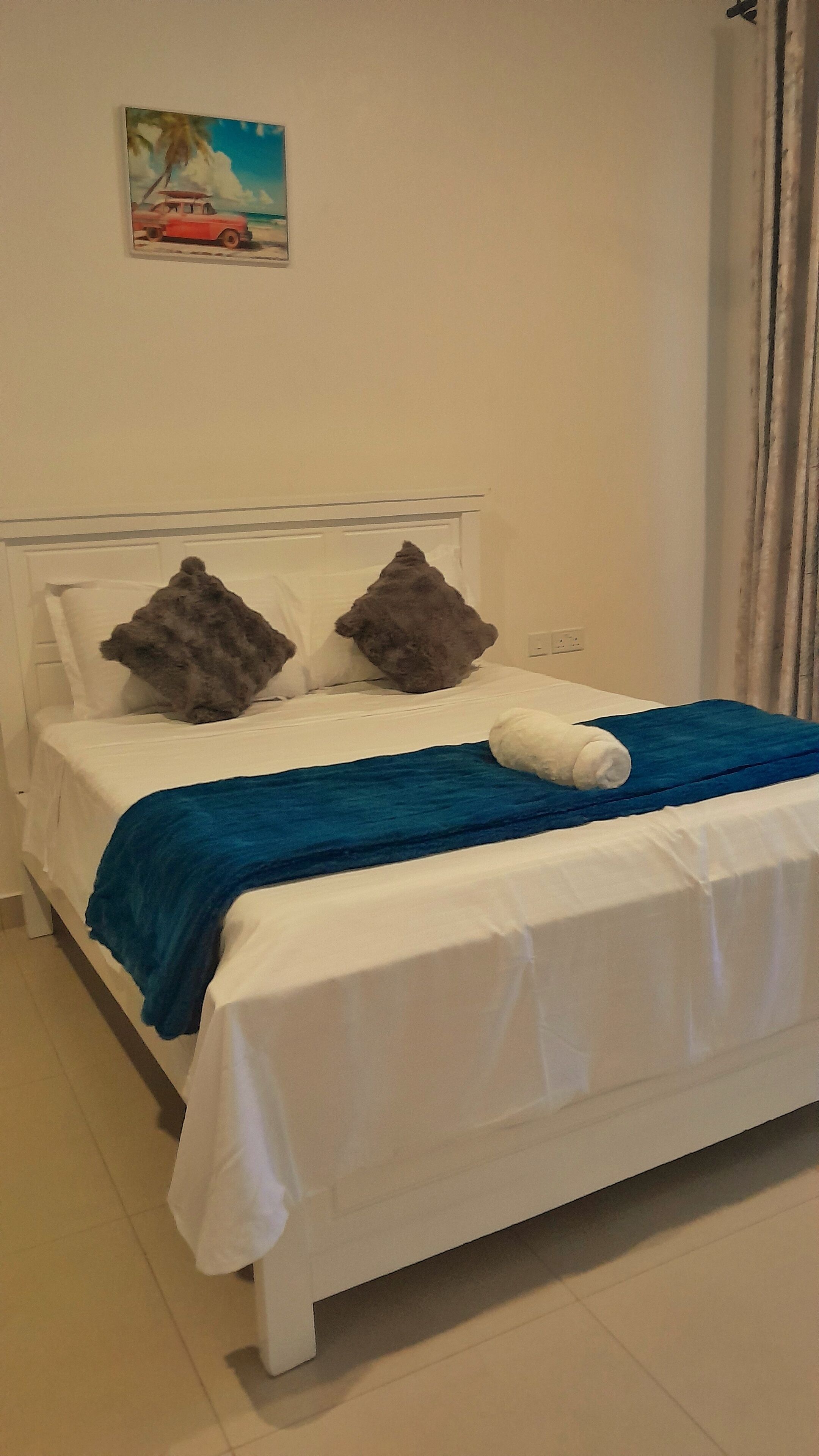 Ein Bett mit weißer Bettwäsche, zwei grauen Kissen und einer blauen Decke.