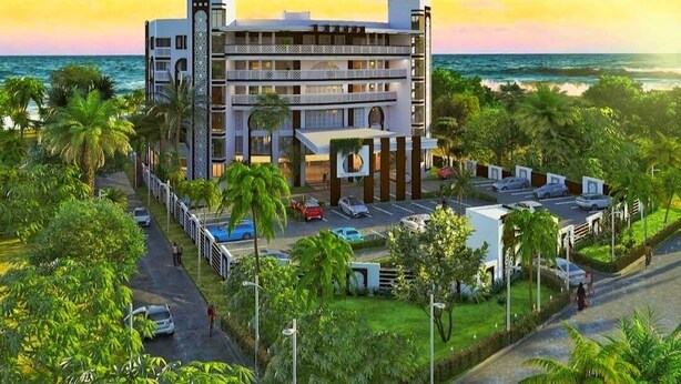 A multi-story hotel with a central courtyard, surrounded by lush greenery and a view of the ocean. - Nyali Beachfront Apartments Baobab waves (Mombasa)