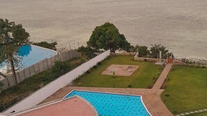 A swimming pool with a view of the sea, surrounded by a landscaped area with a circular garden and a pathway. - Nyali Beachfront Apartments Baobab waves (Mombasa)