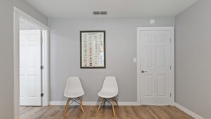 Une pièce avec deux chaises blanches, une affiche encadrée représentant différentes espèces de poissons et deux portes blanches.