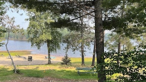 Udsigt over en sø med en privat strand, picnicborde og et skilt der angiver 'Villas Private Beach'.