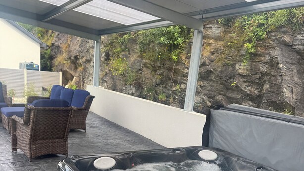 A hot tub with water flowing, surrounded by wicker furniture and a covered patio area.